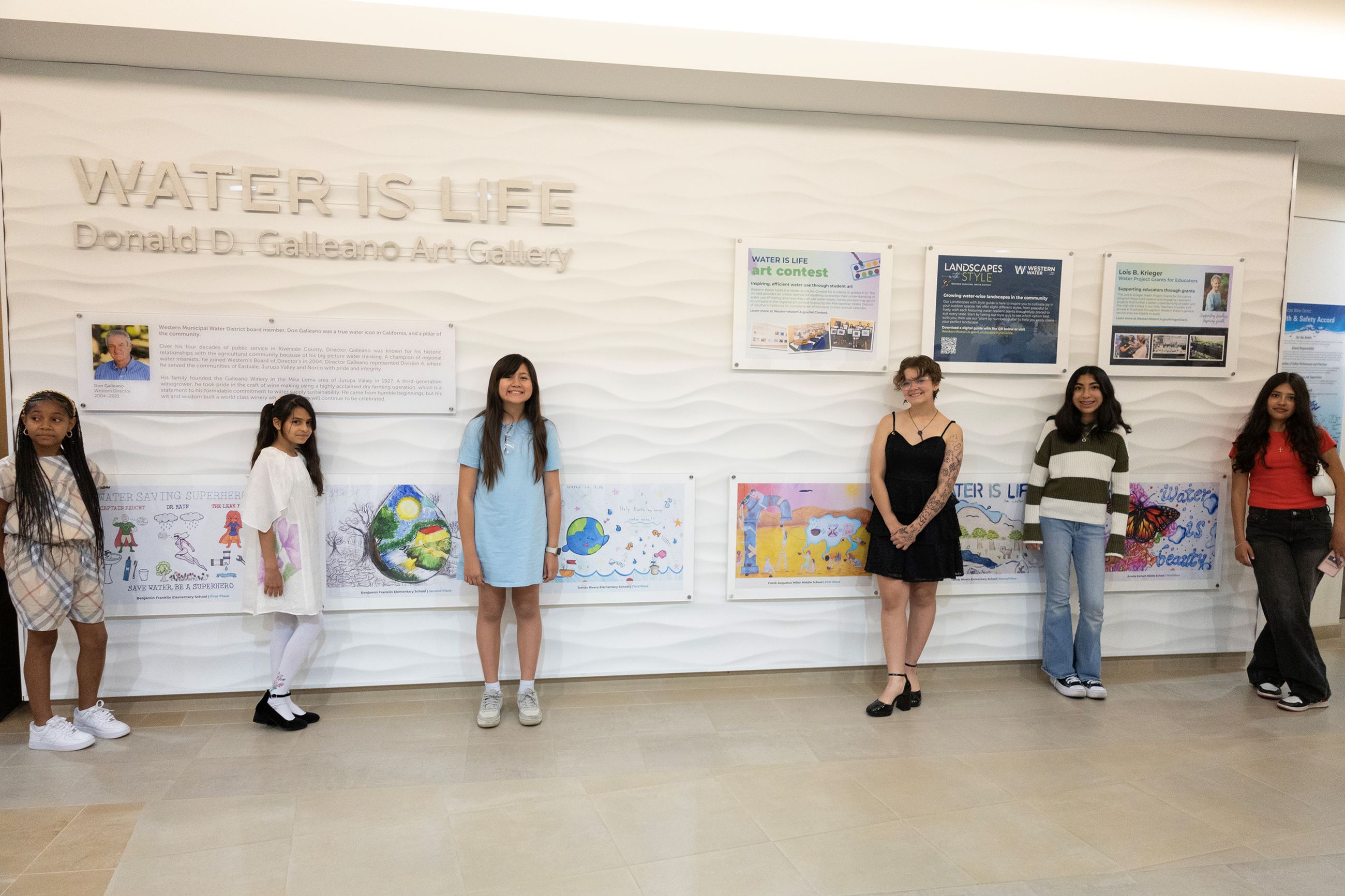 Art contest winners standing next to their hung art on display at the Western Water Facility
